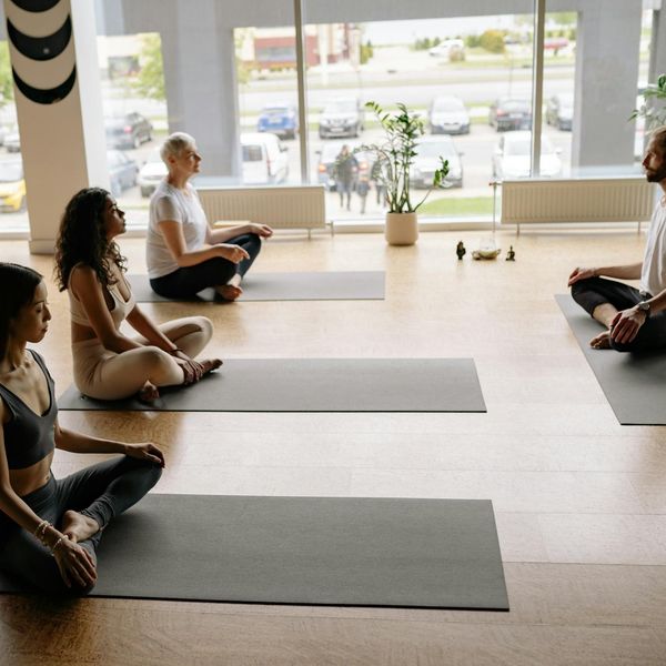 Man meditating peacefully after a workout session, sitting by a large window.