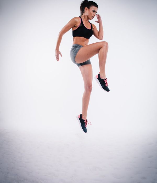 Woman in activewear performing a calm cardio movement in a minimalist studio.